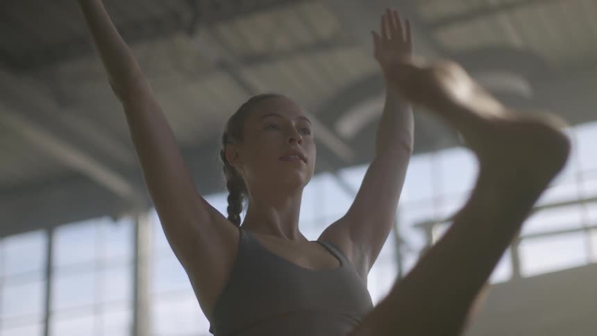 Young woman stretching on a yoga pose inside a gym at morning