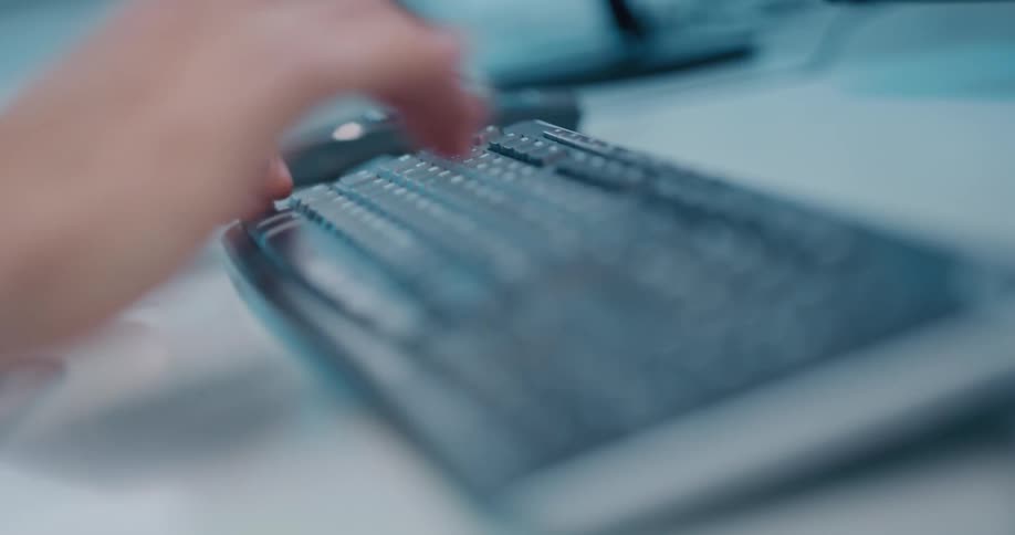 A person sitting at a desk typing on a keyboard