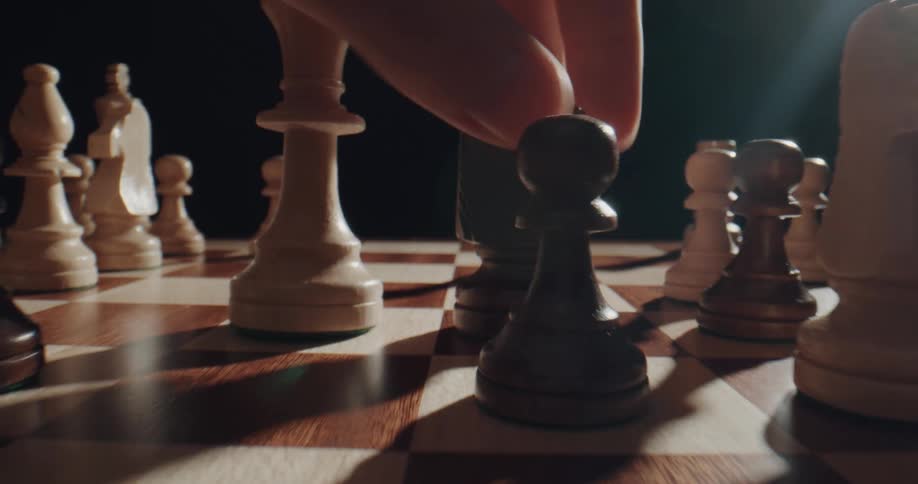 A chess player quickly moves pieces while playing in a room with bright sunlight