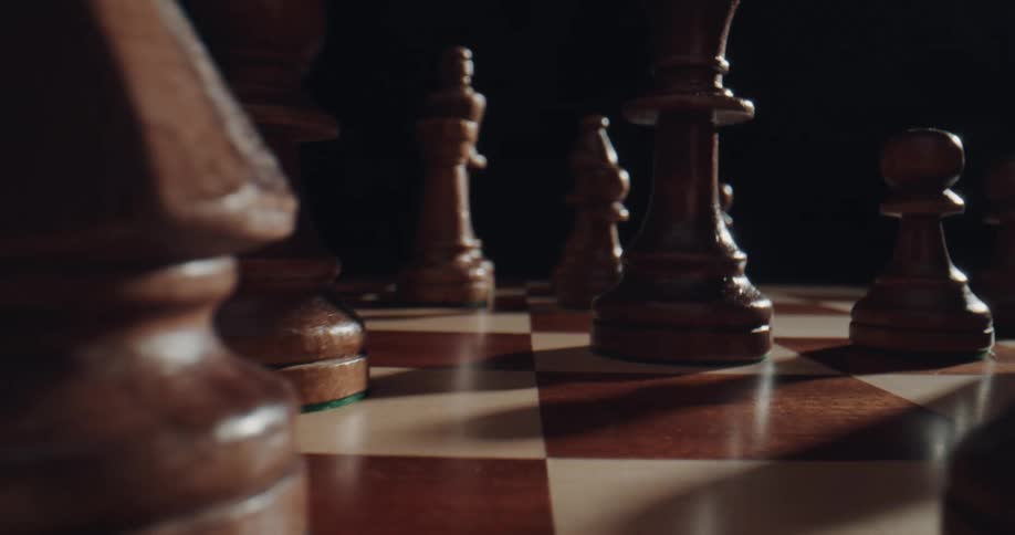 A close up of a chess board with hands moving the pieces on the board