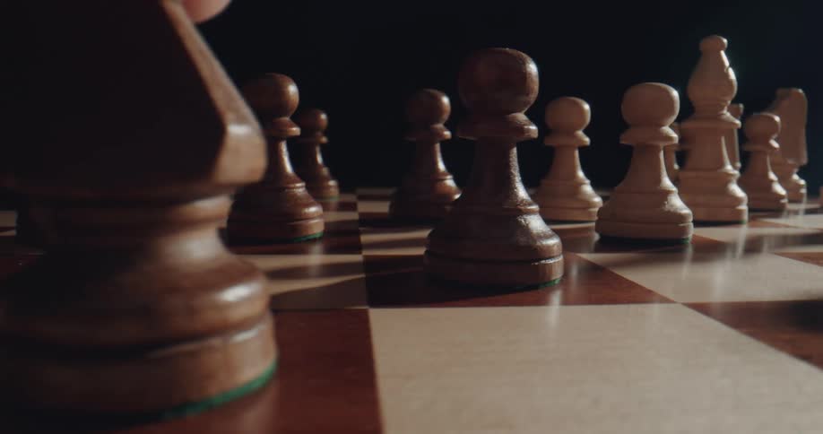 A person moves a chess piece on a chess board