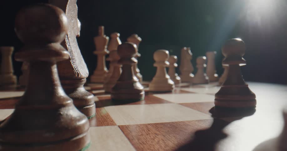 A hand sliding a chess piece across a chessboard