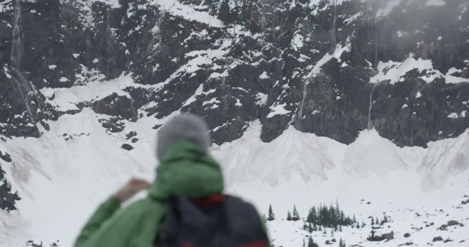 A man looking around at snow-covered mountains