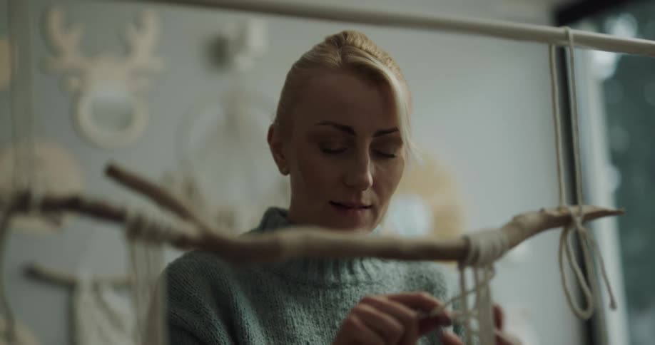 A woman hand crafting decorations using white string and twigs