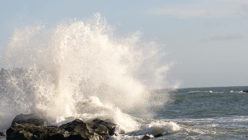 Waves are crashing against rocks by the shore