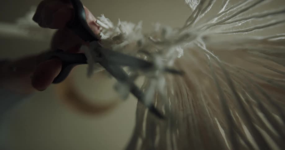 A person is cutting hanging pieces of string