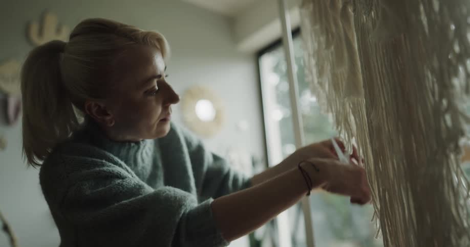 Woman shaping the fringes of a hand made decoration using scissors