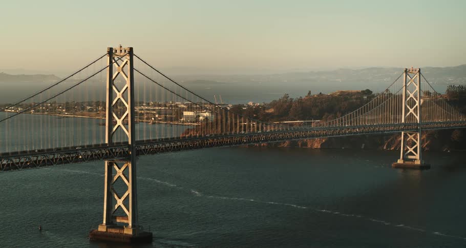 A view of a bridge going into a city with cars driving across it