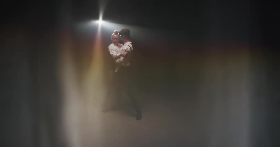 Couple behind a gauze dancing tango in front of a spotlight