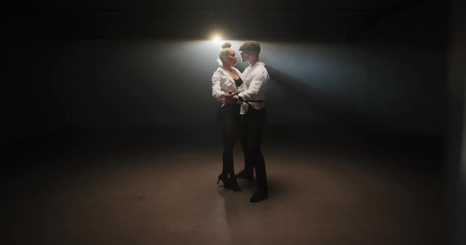 Young couple behind a veil dancing tango on a stage under a spotlight