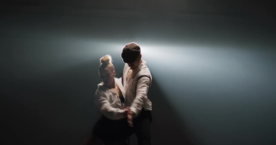 Couple dancing tango in front of a spotlight on the stage