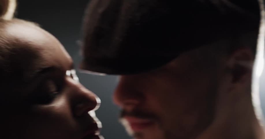 A man and woman dance intimately under a light in a dark place