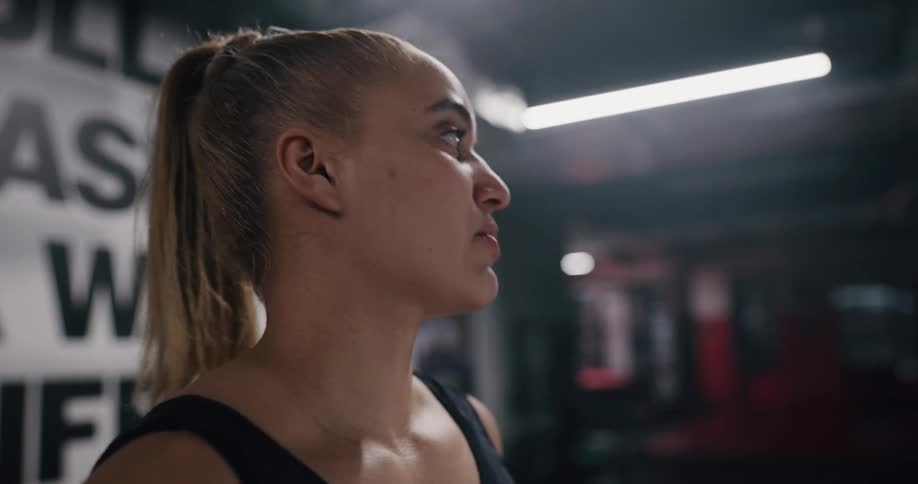A woman is standing in a gym while wearing a pony tail