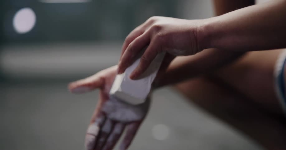 A person in the gym rubs chalk onto their hands