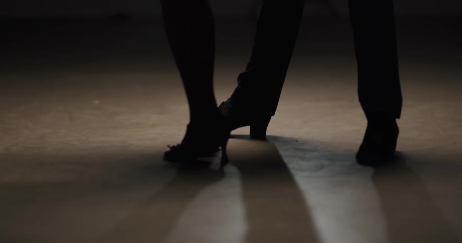 A man and woman salsa dancing on a hard floor
