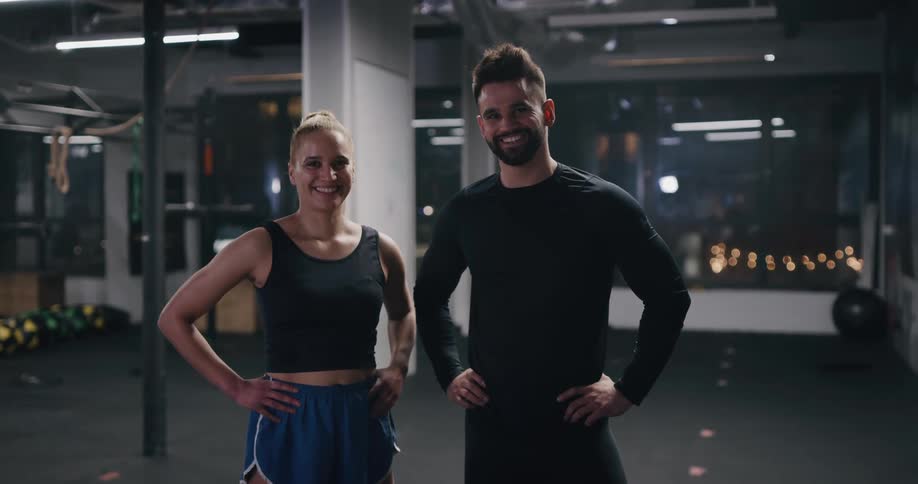 Two people pose and smile in the gym