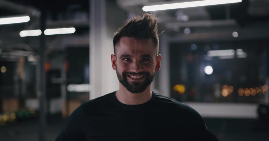 A man stands in a gym and smiles
