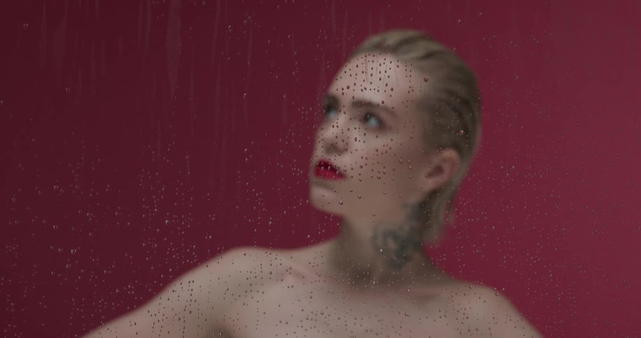 A woman looks around behind the wet glass