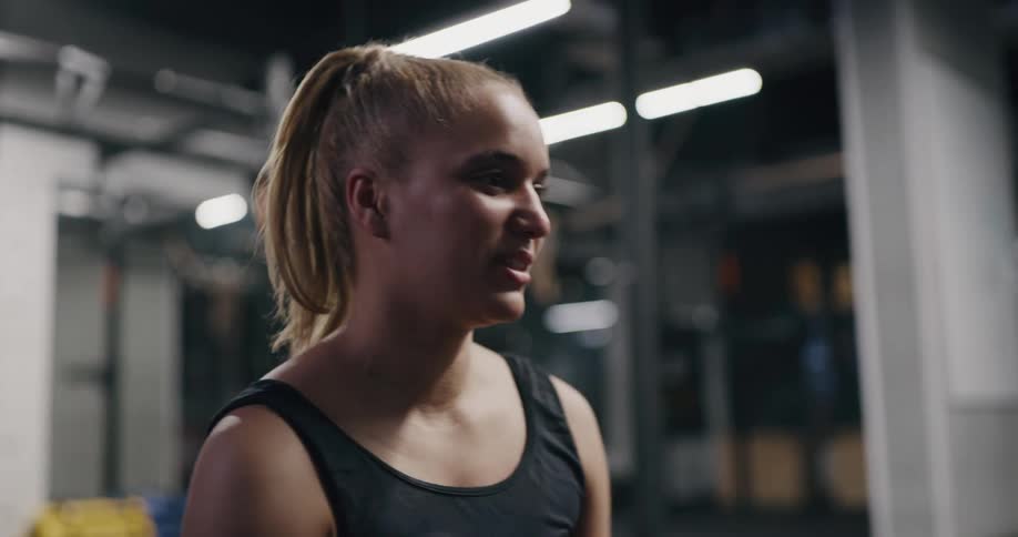 Young fit woman talking to her coach while sitting in the floor of a gym