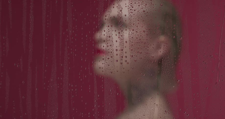 A woman looks up behind the wet glass