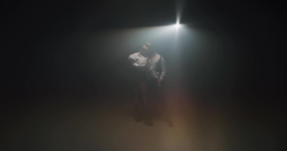 Couple behind a veil pasionately dancing tango on stage in front of a spotlight