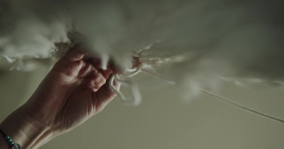 Hands are typing white rope in a macrame fashion
