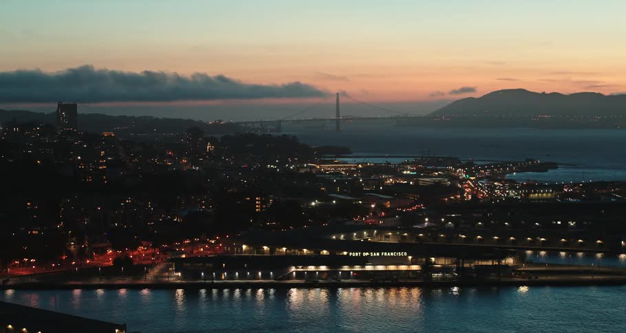 Aerial view of the water and port in front of a lit up city skyline