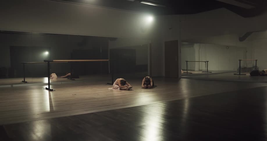 A young ballerina walks with her instructor and the two of them begin stretching exercises together