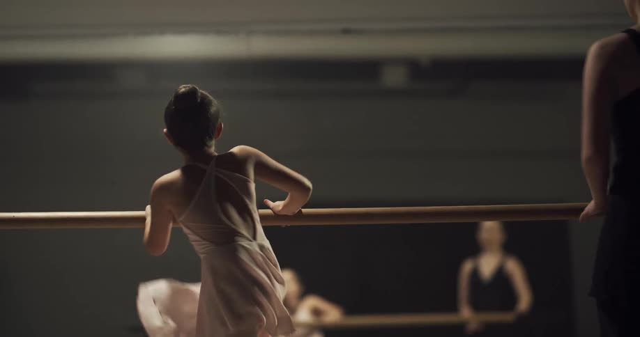 A woman and child kick high as they practice ballet
