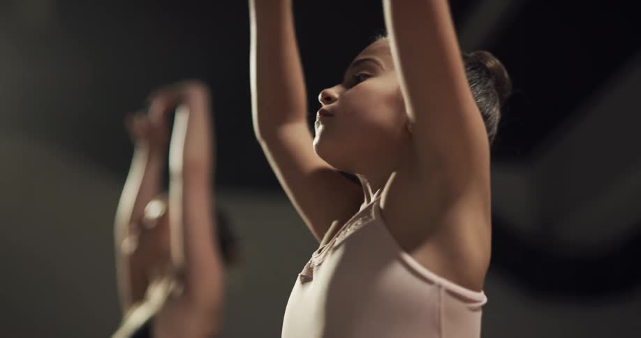 A woman instructing a girl on dancing ballet with mirrors and a door in the background