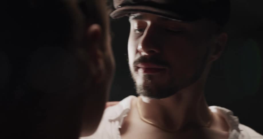 A man pushes a shirt aside revealing his dance partners bare shoulder as they dance and touch