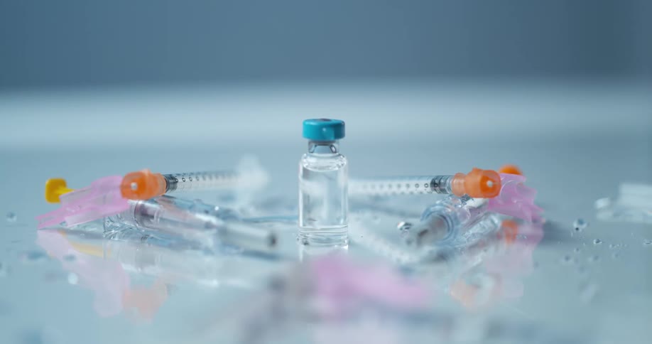 A vial of medication and syringe needles flying off of a white table