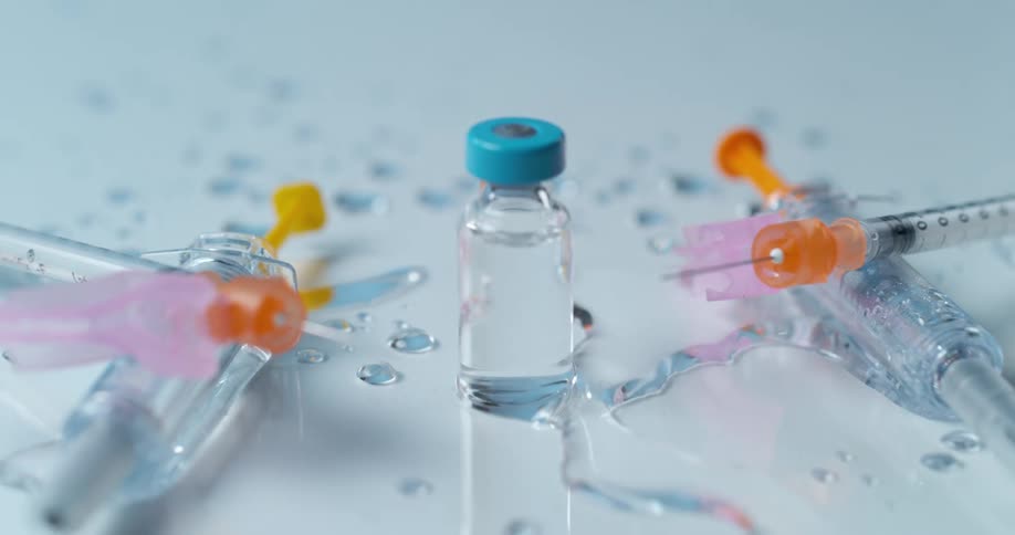 A table with liquid droplets syringes and a bottle