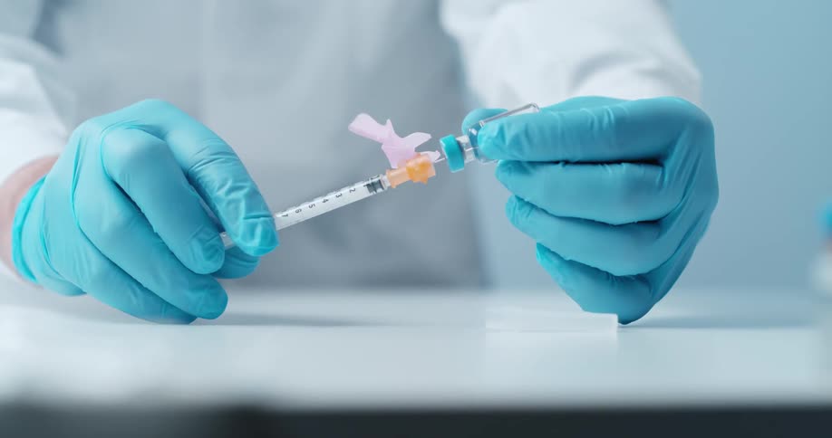 A syringe stabbing a vile and sucking in a liquid