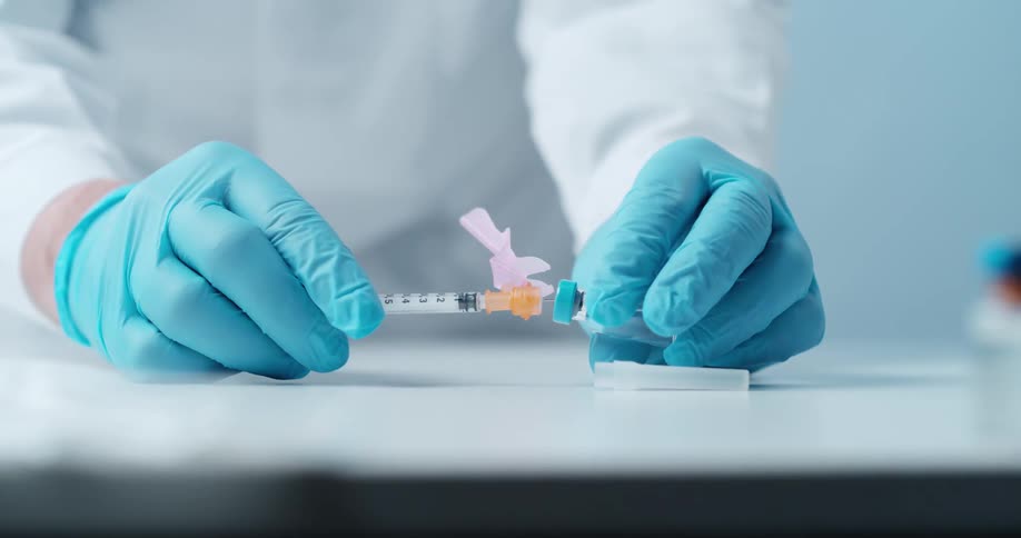 A person is filling a syringe from a vial