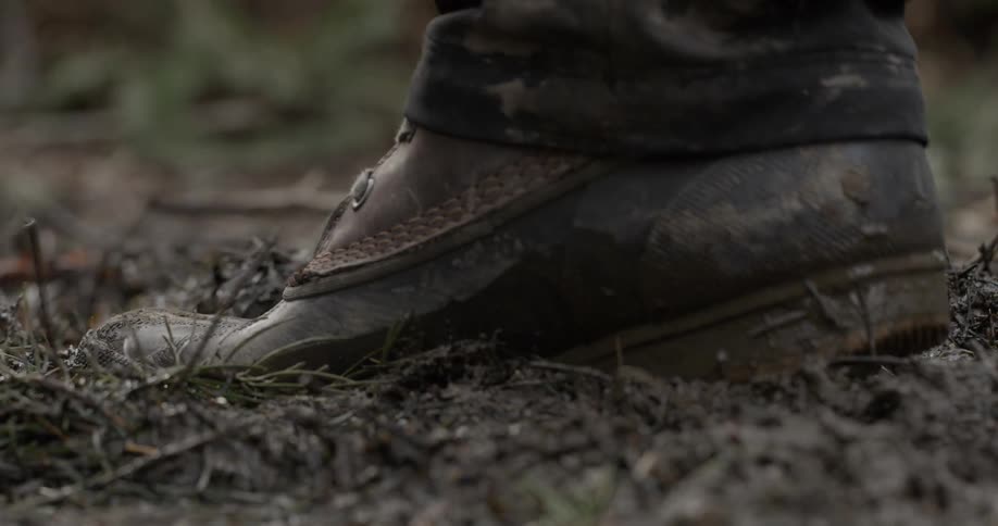 A hiking boot steps in squishy mud
