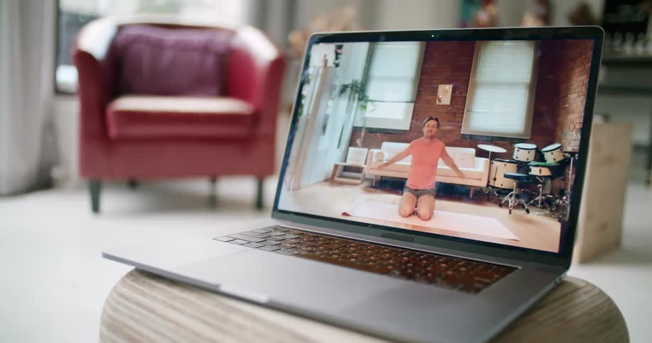 A laptop computer is open an video of a man shows him stretching his arms before exercising