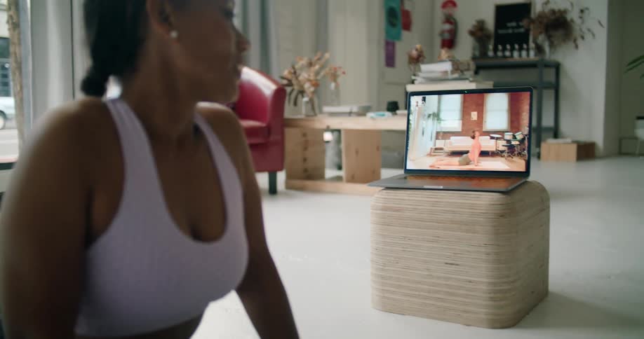 A woman is watching a exercise video and training along with it indoors