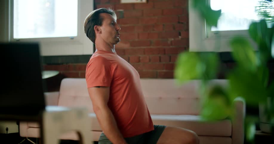 A man is doing yoga while he talks on his laptop