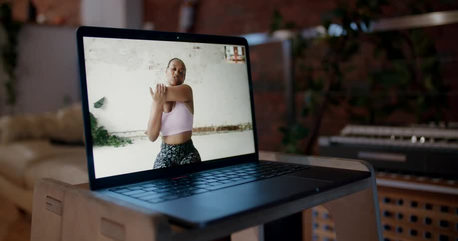 A laptop with a woman stretching on it sits inside a home
