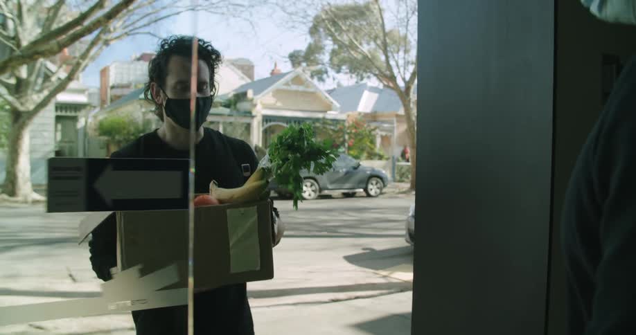 A man wearing a face mask makes a groceries delivery to a client