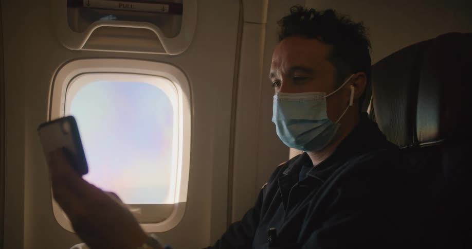 A man with a phone sitting on an airplane
