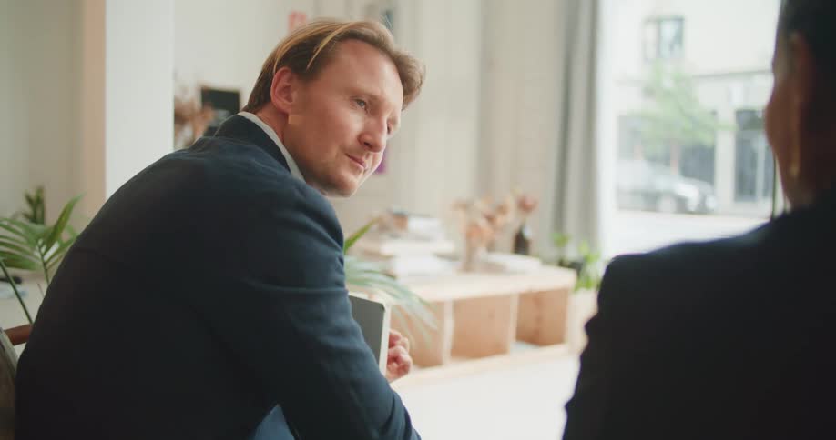 A man nods in agreement as he listens to the woman sitting beside him in a room during the day