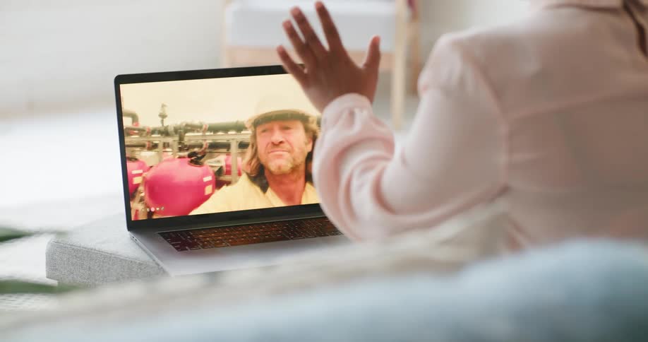 A woman is talking with a man on a work site through the laptop