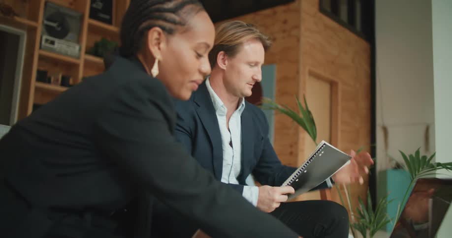 A man and woman in suits looking at a laptop