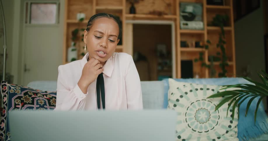 A woman is talking on her laptop as she sits on the couch