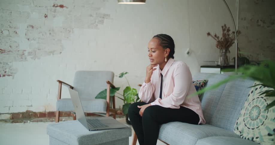 A woman is talking on a laptop and sitting on a couch