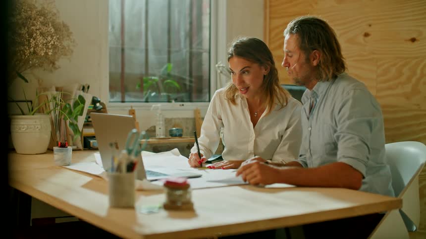 Two people having a meeting in an office talking and pointing to a laptop in a desk