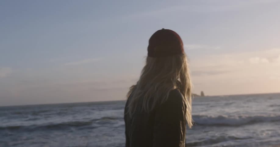 A woman walks along the water of a beach