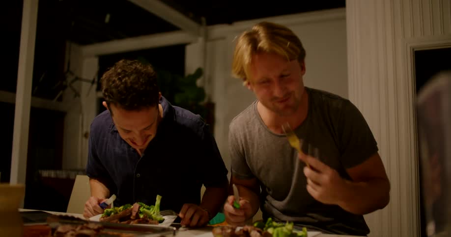 Two men are eating dinner in a house together